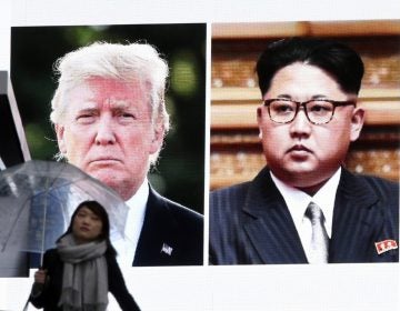A woman walks by a huge screen showing U.S. President Donald Trump, left, and North Korea's leader Kim Jong Un, in Tokyo, Friday, March 9, 2018. (Koji Sasahara/AP Photo)