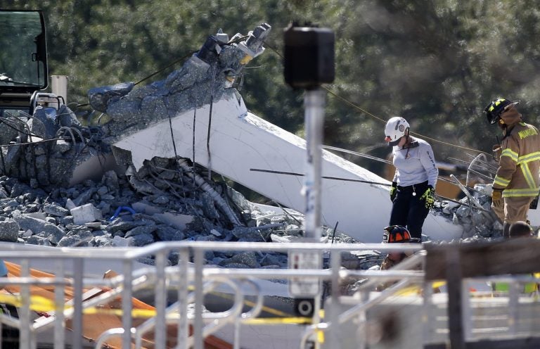 Rescue workers walk on the rubble after a brand-new pedestrian bridge collapsed at Florida International University in Miami on Thursday, March 15, 2018. The pedestrian bridge collapsed onto a highway crushing multiple vehicles and killing several people. (Wilfredo Lee/AP Photo)