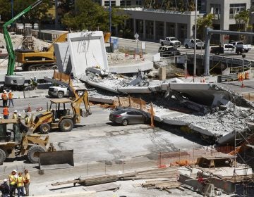 Crushed cars are shown under a section of a collapsed pedestrian bridge, Friday, March 16, 2018 near Florida International University in the Miami area. The new pedestrian bridge that was under construction collapsed onto a busy Miami highway Thursday afternoon, crushing vehicles beneath massive slabs of concrete and steel, killing and injuring several people, authorities said. (Wilfredo Lee/AP Photo)
