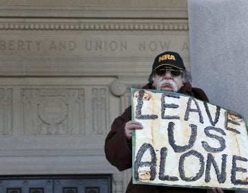 A man holds a sign as he stands outside the War Memorial, near a group of Second Amendment advocates gathered in opposition to about a half-dozen gun control bills expected to get a vote in the Assembly on Monday, March 26, 2018, near the Statehouse in Trenton, N.J.