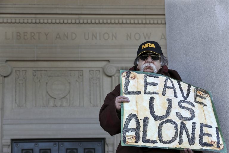 A man holds a sign as he stands outside the War Memorial, near a group of Second Amendment advocates gathered in opposition to about a half-dozen gun control bills expected to get a vote in the Assembly on Monday, March 26, 2018, near the Statehouse in Trenton, N.J.