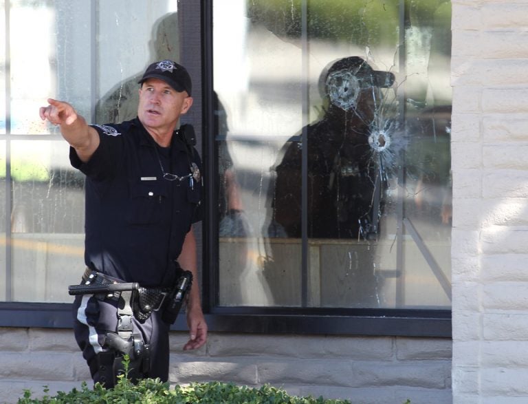 With bullet holes seen in a window, officers look for evidence at the scene of a shooting at an IHOP restaurant in Carson City, Nev. on Tuesday, Sept. 6, 2011. Seven people were wounded after a gunman opened fire at the restaurant, authorities said. (Cathleen Allison/AP Photo)