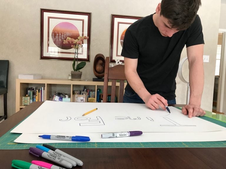 Ethan Block, 16, of Pennington, New Jersey, makes a sign with the slogan 