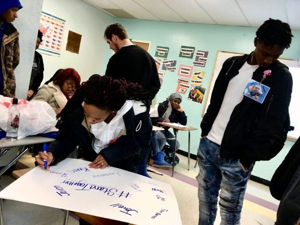 Freire Charter School students write the names of people they lost to gun violence on a poster.