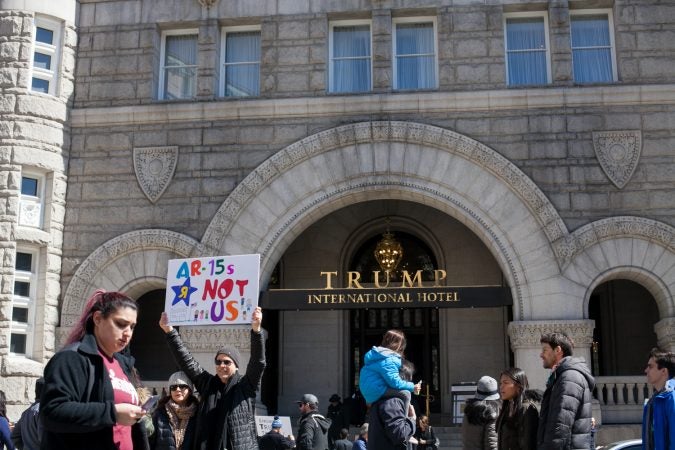Demonstrators pass by the Trump International Hotel in downtown Washington D.C. Saturday afternoon during the March for Our Lives. (Brad Larrison for WHYY)