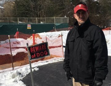 T.J. Allen, a resident of West Whiteland Township in Chester County, stands in front of sinkhole enclosures in his back yard. Allen said he's worried about the sinkholes, and the fact that Sunoco has been ordered to make sure an existing pipeline that runs through his neighborhood is safe. (Jon Hurdle/StateImpact Pennsylvania)