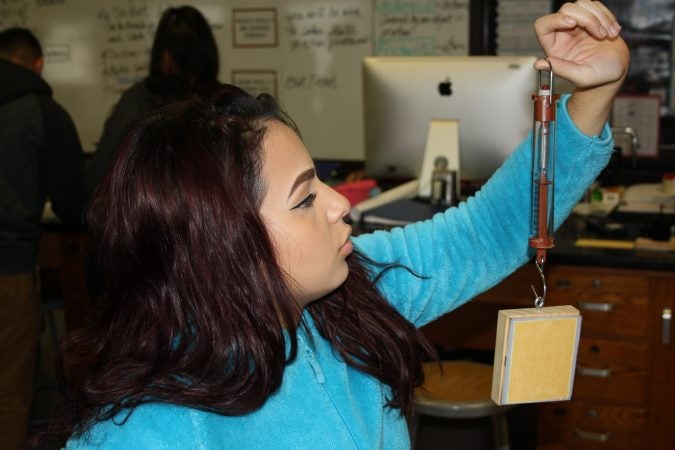Eunice Millán prepares to measure the force of friction in a physics lab at Woodrow Wilson High School in Camden, New Jersey, which requires all students to take physics to graduate. (Tara García Mathewson/The Hechinger Report)