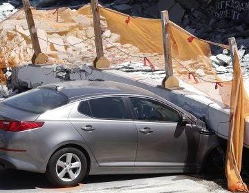A crushed car sits under a section of a collapsed pedestrian bridge on Friday near Miami. Authorities are still investigating the cause.
(Wilfredo Lee/AP)