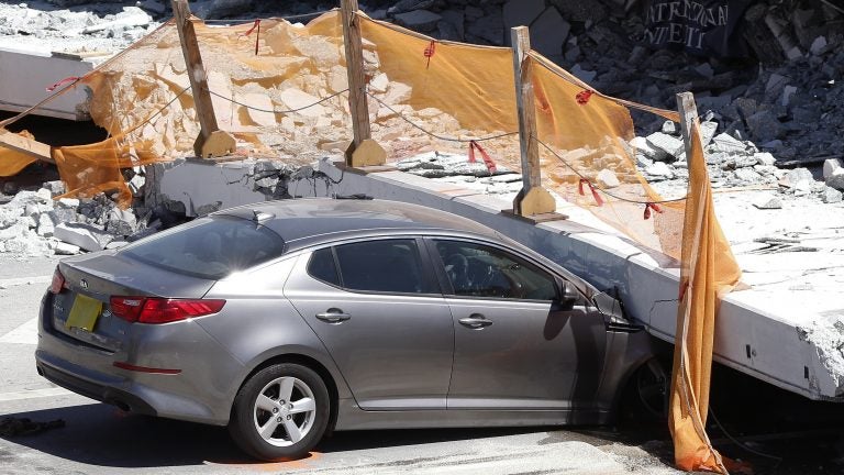 A crushed car sits under a section of a collapsed pedestrian bridge on Friday near Miami. Authorities are still investigating the cause.
(Wilfredo Lee/AP)