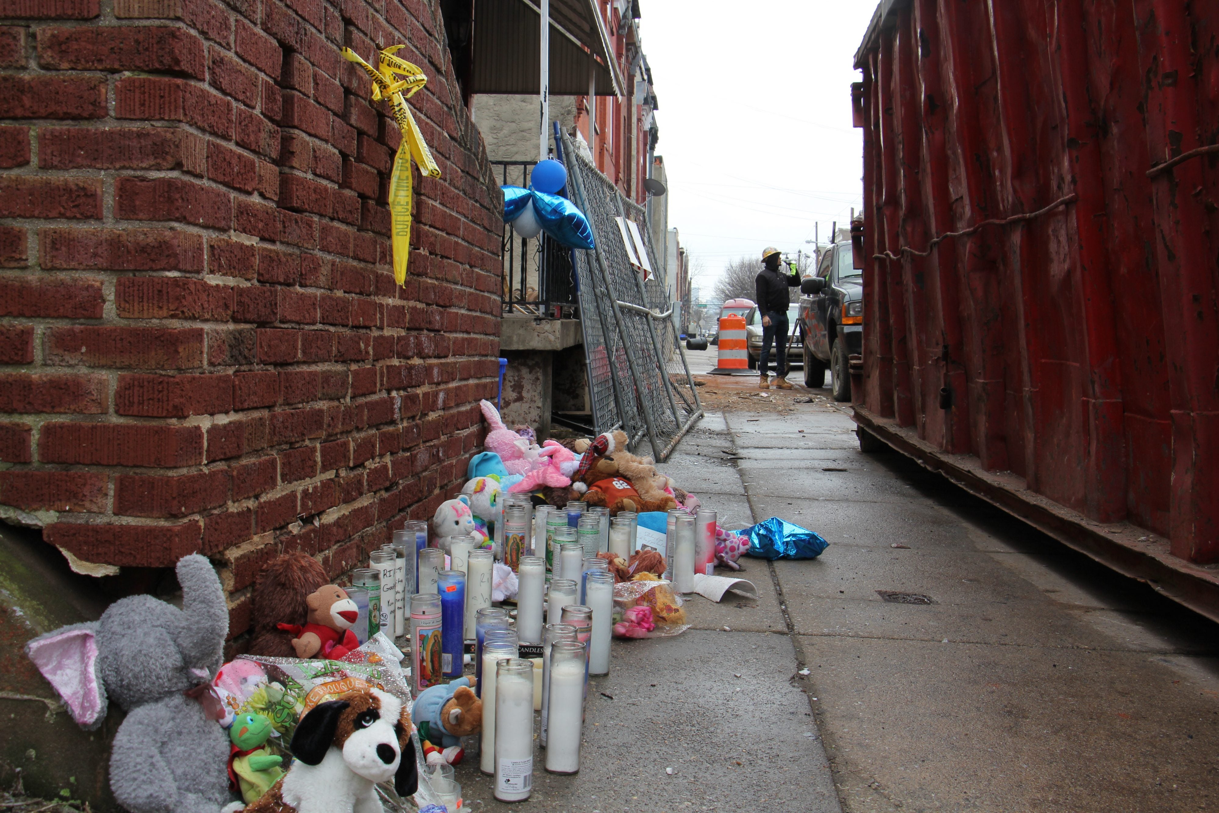 Balloons, candles and plush toys memorialize the four people killed in the house fire.