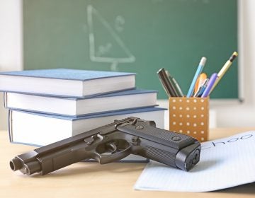 School stationery and gun on table in class