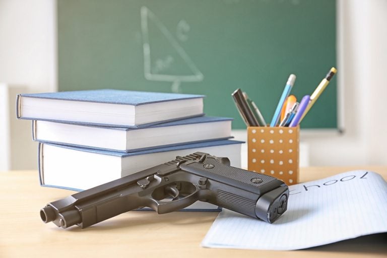 School stationery and gun on table in class