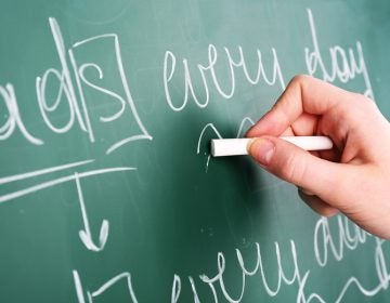 Teacher hand writing grammar sentences on blackboard background