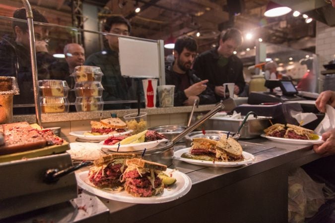 Patrons line up to pay as their sandwiches are readied. (Emily Cohen for WHYY)