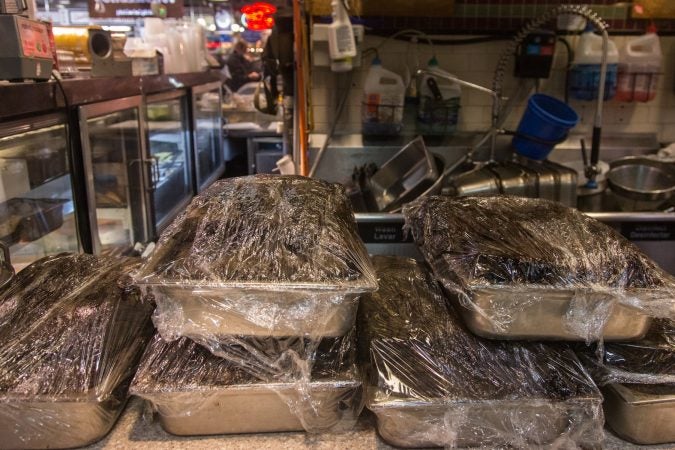 Pans of Pastrami sit on the countertop waiting to be placed into an oven. In anticipation for an influx of customers from the Flower Show, Hershel’s East Side Deli has doubled their meat preparation. (Emily Cohen for WHYY)