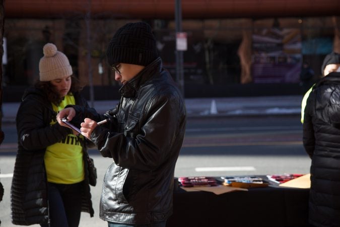 A young man registers to vote. Volunteers with registration information and forms lined the march route as Philadelphians of all ages participated in the city's March for Our Lives, March 24, 2018. (Emily Cohen for WHYY)