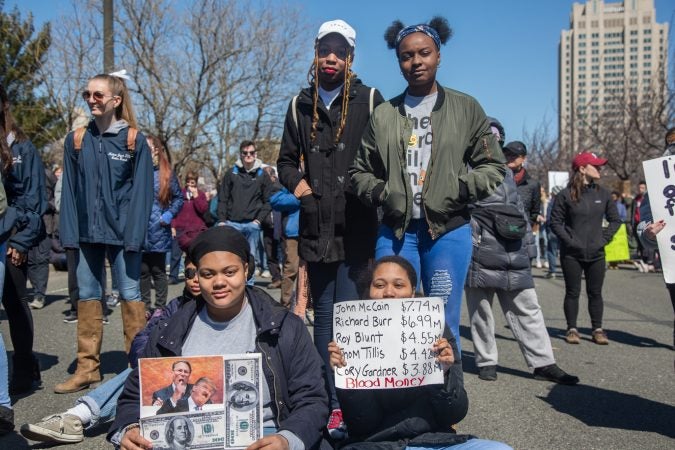 A group of friends sit and stand as they listen to the speakers at the Philadelphia March for Our Lives, March 24, 2018. (Emily Cohen for WHYY)