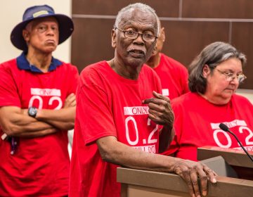 Robert Taylor, (center), speaks at a St. John the Baptist Parish council meeting in 2017. He and the other members of the citizens' group around him wear T-shirts that reference the safety limit for the chemical chloroprene. (Julie Dermansky)