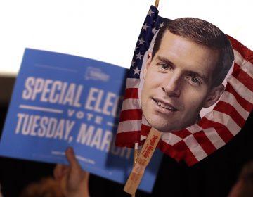 Supporters of Conor Lamb hold signs during his election night party