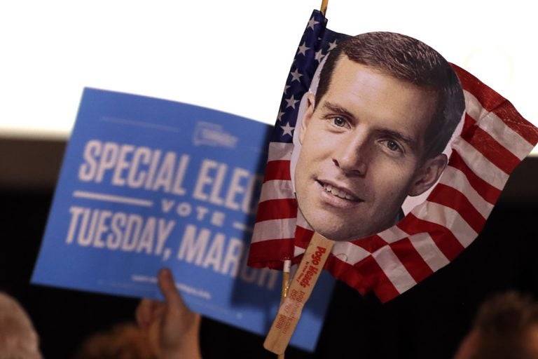 Supporters of Conor Lamb hold signs during his election night party