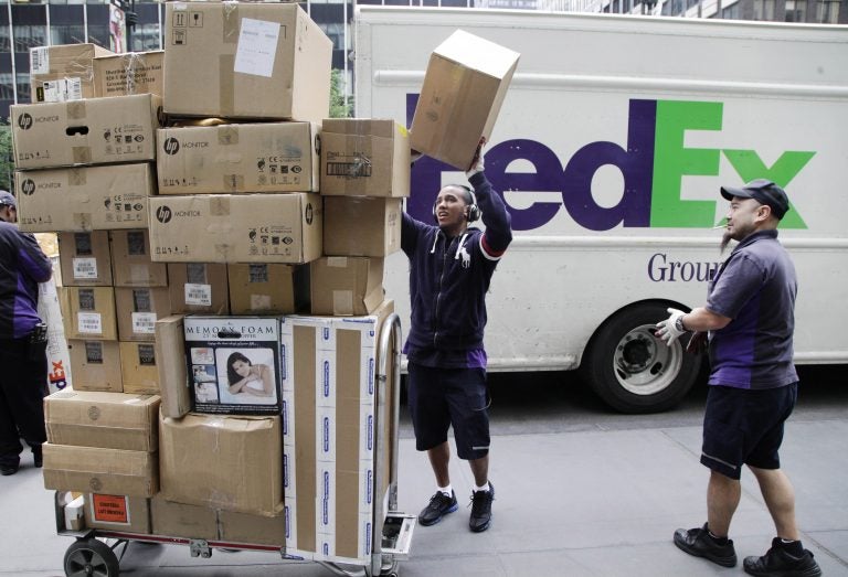 FedEx workers sort boxes for delivery on a busy street.