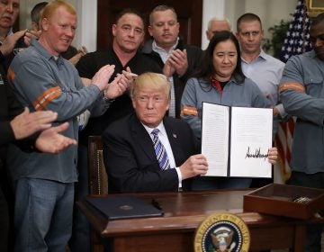 Surrounded by steel and aluminum workers, President Trump holds up the order on steel imports that he signed in Roosevelt Room the the White House on Thursday.
(Chip Somodevilla/Getty Images)