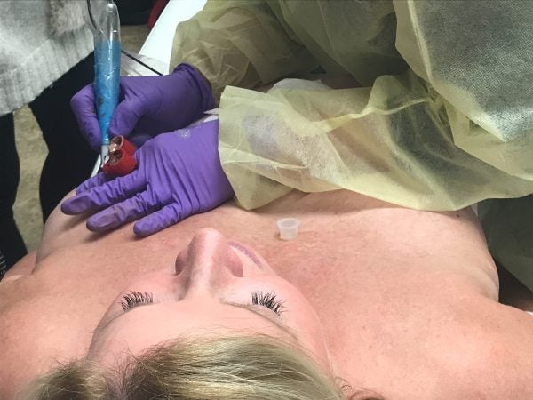 Rose Marie Beauchemin Verzella tattoos a hyper-realistic nipple and areola on Maureen Matteis-Bilbee, who recently had a mastectomy followed by reconstructive surgery. (Abby Holtzman for WHYY) 