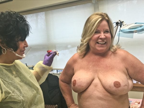 Rose Marie Beauchemin Verzella takes a final look at Maureen Matteis-Bilbee's completed nipple tattoos. (Abby Holtzman for WHYY) 