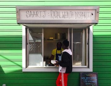 

A customer approaches the window at Saartj, a pop-up food stall in New Orleans running a social experiment. Customers of color are charged the listed $12 price for a meal. White customers are told about the income gap in New Orleans between whites and African-Americans and asked if they want to pay $30 instead, a price that reflects the gap. (Deji Osinulu)