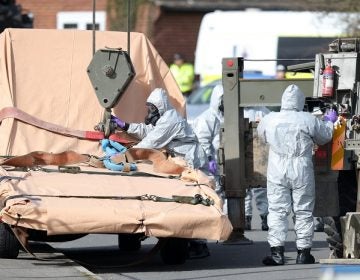 Soldiers wearing protective clothing prepare to lift a tow truck in Hyde Road, Gillingham, Dorset, England as the investigation into the suspected nerve agent attack on Russian double agent Sergei Skripal continues Wednesday March 14, 2018.  The army cordoned off a road in Dorset on Wednesday as the investigated the attack on Sergei Skripal and his daughter Yulia. Authorities have cordoned off several sites in and near Salisbury, 90 miles (145 kilometers) southwest of London as part of their probe.  (Andrew Matthews/PA via AP)