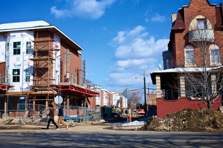 Two young men walk past a rehab project in Strawberry Mansion, in 2018.