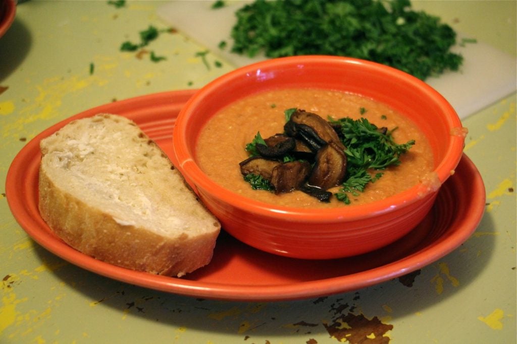 Almost-instant chickpea-tomato soup is served with a garnish of parsley and shitake bacon and a slice of Italian bread with homemade butter made from soy lecithin and coconut oil. (Emma Lee/WHYY)