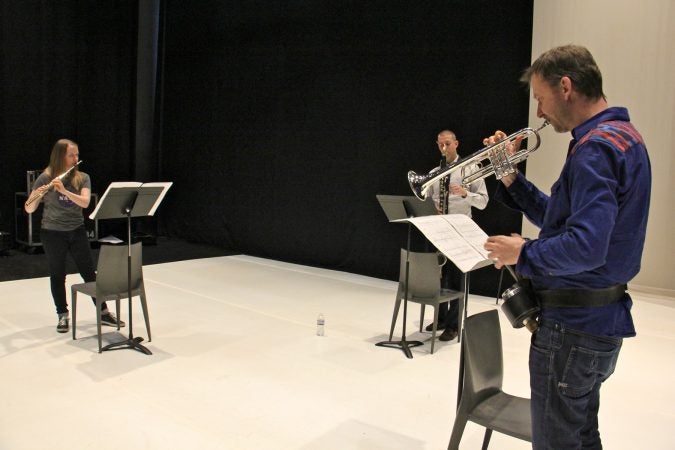 Performing Schönheit, (from left) Emma Resmini, flute, Sean Bailey, bass clarinet, and Marco Blaauw,  trumpet, rehearse on the Fringe Arts stage. (Emma Lee/WHYY)