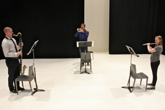 Performing Schönheit, (from left) Sean Bailey, bass clarinet, Marco Blaauw, trumpet, and Emma Resmini, flute, rehearse on the Fringe Arts stage. (Emma Lee/WHYY)