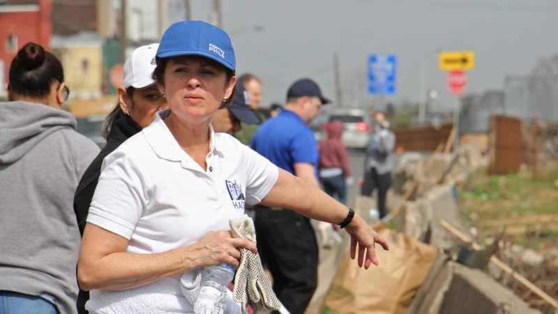 Maria Gonzalez, president of HACE, directs cleanup efforts along Gurney Street near the Conrail tracks, site of a former heroin encampment. (Emma Lee/WHYY)