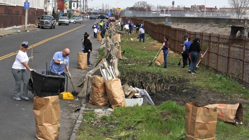 About 30 workers and volunteers clean up trash along Gurney Street near the former site of a notorious heroin encampment. (Emma Lee/WHYY)