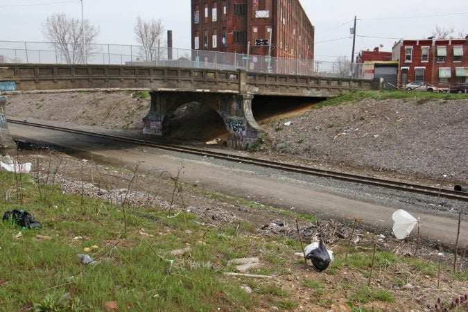 The site of the former heroin camp along the Conrail tracks and under the A Street bridge, has been cleaned and fenced off. (Emma Lee/WHYY)