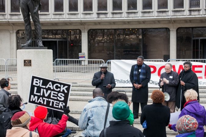 Mark Tyler of the oragnization, POWER, speaks to demonstrators gathered in front of the Philadelphia Police Department Headquarters Thursday before marching up Market Street in response to an incident where two black men who were arrested in a Center City Starbucks last week. (Brad Larrison for WHYY)