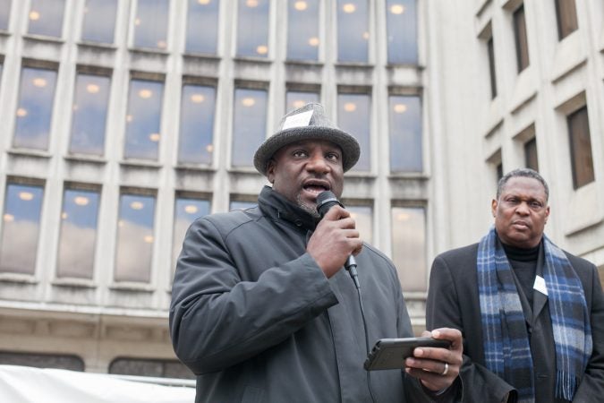Mark Tyler of the oragnization, POWER, speaks to demonstrators gathered in front of the Philadelphia Police Department Headquarters Thursday before marching up Market Street in response to an incident where two black men who were arrested in a Center City Starbucks last week. (Brad Larrison for WHYY)