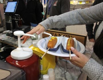 A customer adds mustard to corn dogs at Fox and Son at Reading Terminal Market. (Emma Lee/WHYY)