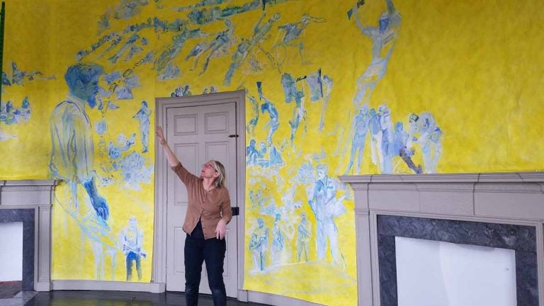 Artist Jane Irish explains how she painted one of the oval rooms in the Lemon Hill mansion to depict an anti-war demonstration that took place in Valley Forge, in 1970. (Peter Crimmins/WHYY)