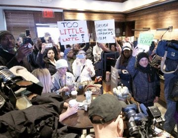 People gather at a Starbucks on 18th and Spruce streets in Philadelphia to protest Thursday's controversial arrests of two black men at the store. (Bastiaan Slabbers/for WHYY)