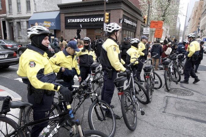 Philadelphia police officers stand by as people gather outside a Starbucks on 18th and Spruce streets in Philadelphia to protest Thursday's controversial arrests of two black men. (Bastiaan Slabbers/for WHYY)