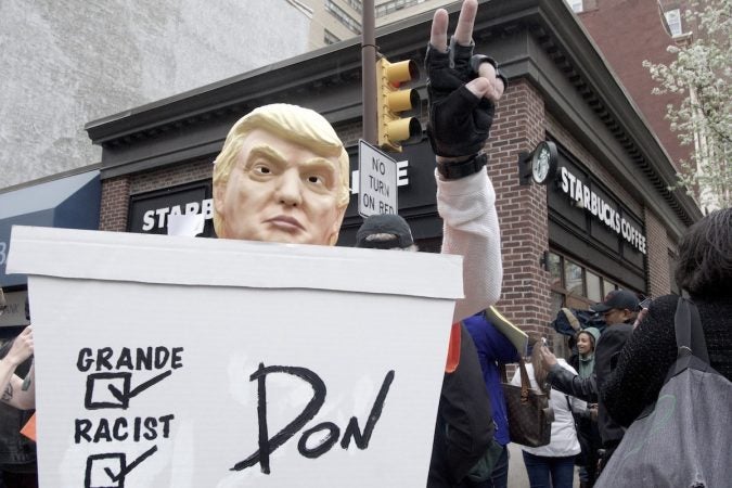 Mike Hisey, wearing a Trump mask, protests outside a Starbucks on 18th and Spruce streets in Philadelphia. (Bastiaan Slabbers/for WHYY)