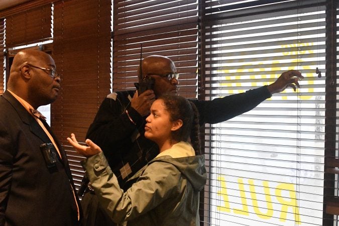 A Civil Affairs officer shuts the blinds after an unidentified protestor opened them inside the Starbucks on 18th and Spruce streets on Monday Morning. (Bastiaan Slabbers for WHYY)