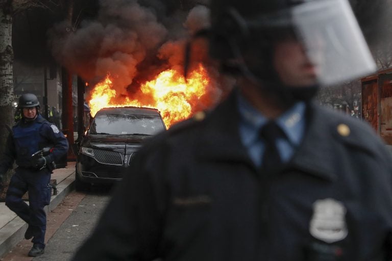 A parked limousine burns as riot police clear the street during a demonstration after the inauguration of President Donald Trump, Friday, Jan. 20, 2017, in downtown Washington. Protesters registered their rage against the new president Friday in a chaotic confrontation with police who used pepper spray and stun grenades in a melee just blocks from Donald Trump's inaugural parade route. Scores were arrested for trashing property and attacking officers.  (AP Photo/John Minchillo)