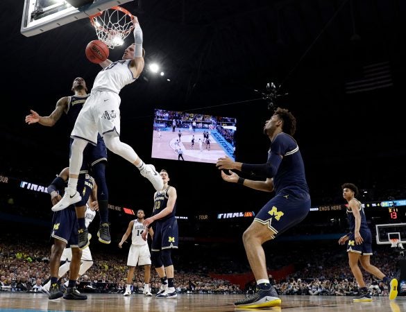 Villanova guard Donte DiVincenzo dunks the ball over Michigan guard Charles Matthews during the first half in the championship game of the Final Four NCAA college basketball tournament, Monday, April 2, 2018, in San Antonio.