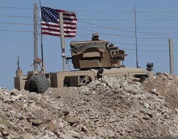 A U.S. soldier sits on an armored vehicle behind a sand barrier at a newly installed position near the tense front line between the U.S-backed Syrian Manbij Military Council and the Turkish-backed fighters, in Manbij, north Syria, Wednesday, April 4, 2018. A week ago, there was just a single house where U.S. soldiers had hoisted a U.S. flag on a hill a little ways back from a tense front line in Syria. Now on Wednesday stood a growing outpost with a perimeter of large sand barriers and barbed wire, a new watch tower and half a dozen armored vehicles, The Associated Press found. (Hussein Malla/AP Photo)