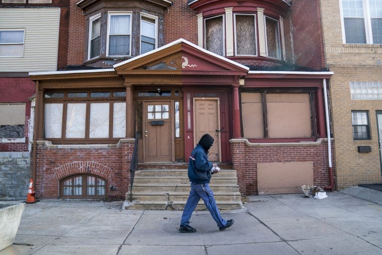 A man walks down a residential street in Strawberry Mansion. (Jessica Kourkounis/WHYY)