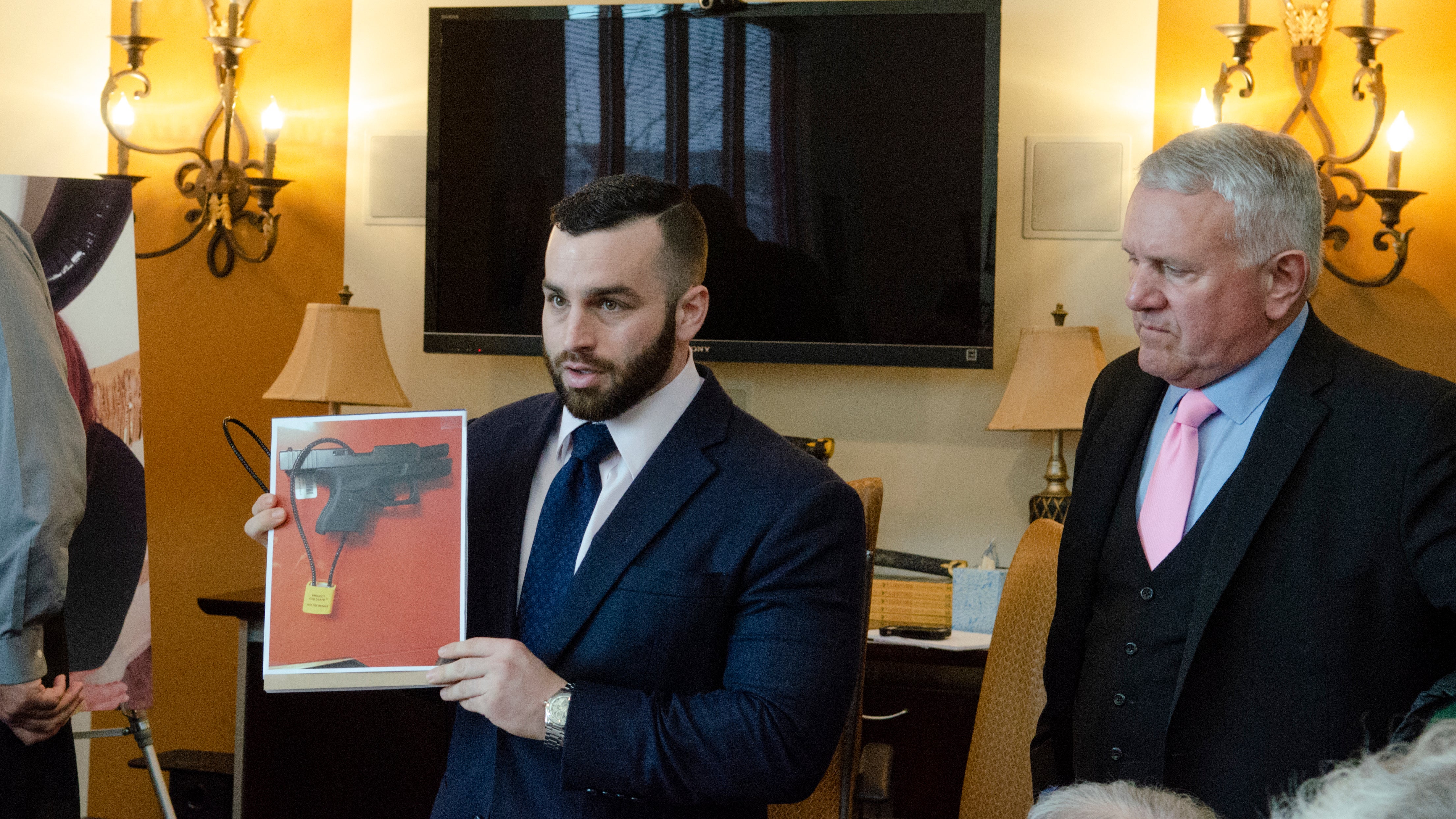 Attorney Oliver Barry shows a photo of a gun lock that might have saved Kelly Ann McDowell's life, as attorney Paul D'Amato looks on. 